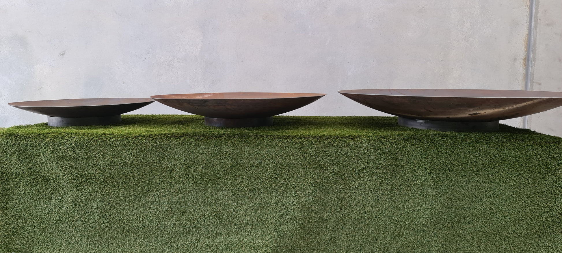Three Corten steel fire pits showing the different sizes.