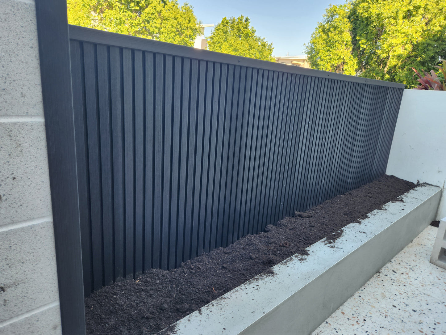 Wpc cladding used to create a small fence, with a flowerbed in front.